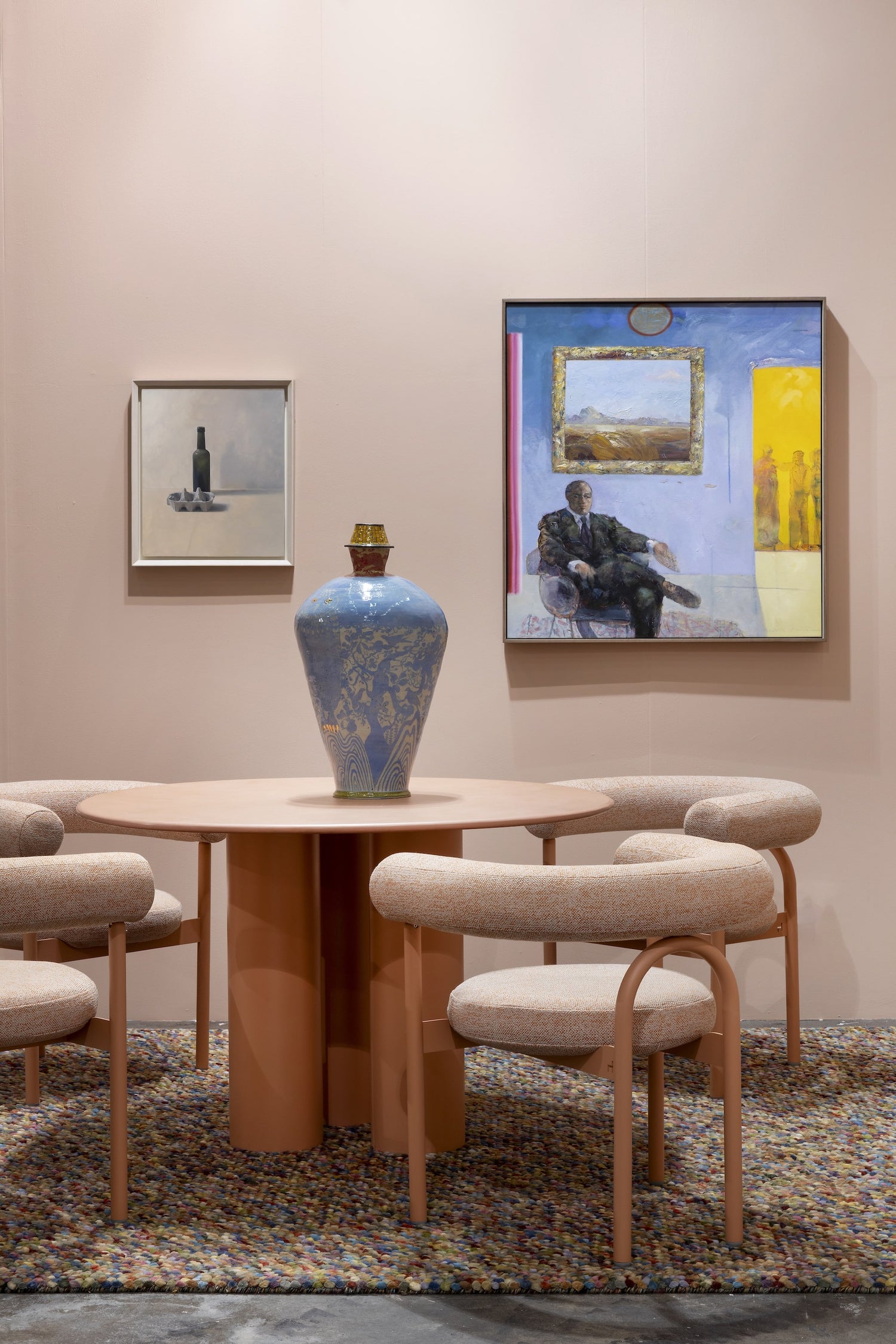 Dining room with a round table and chairs, featuring decorative vases and wall art.